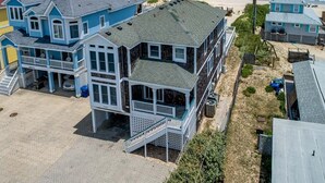 Ein großes, mehrstöckiges Strandhaus mit mehreren Balkonen und einer überdachten Veranda.