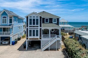 A two-story house with a balcony, a staircase, and a garage. - Stay Salty | Oceanfront | Private Pool, Hot Tub, Dog Friendly | Nags Head (Nags Head)