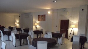A dining area with round tables and white chairs, equipped with lamps and a door in the background. - Le Domaine de Jaugy - Hostel (Gievres)