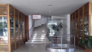 Un hall d’hôtel avec un escalier, un panneau d’accueil et une rambarde en verre.
