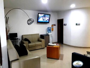 A hotel lobby with a sofa, a coffee table, a TV, and a water dispenser. - Hotel Portobelo Guatape (Guatapé)