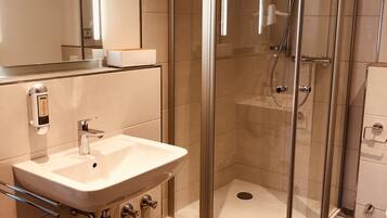 Un baño moderno con ducha acristalada, lavabo blanco y espejo.