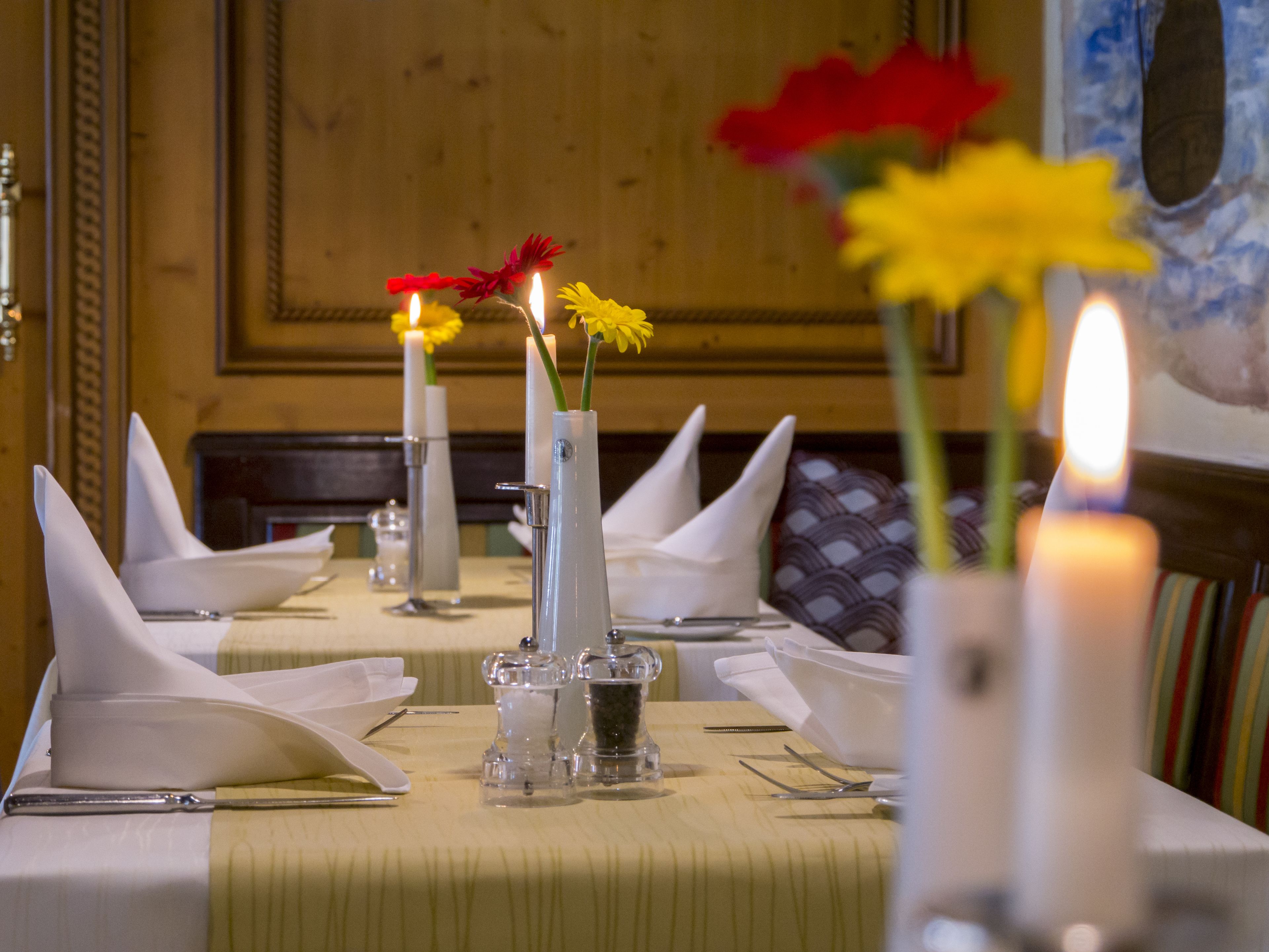 Una mesa de comedor dispuesta con servilletas blancas, cubiertos y velas.