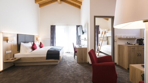 Une chambre d’hôtel comprenant un lit, un bureau, une chaise, une armoire et une lampe.