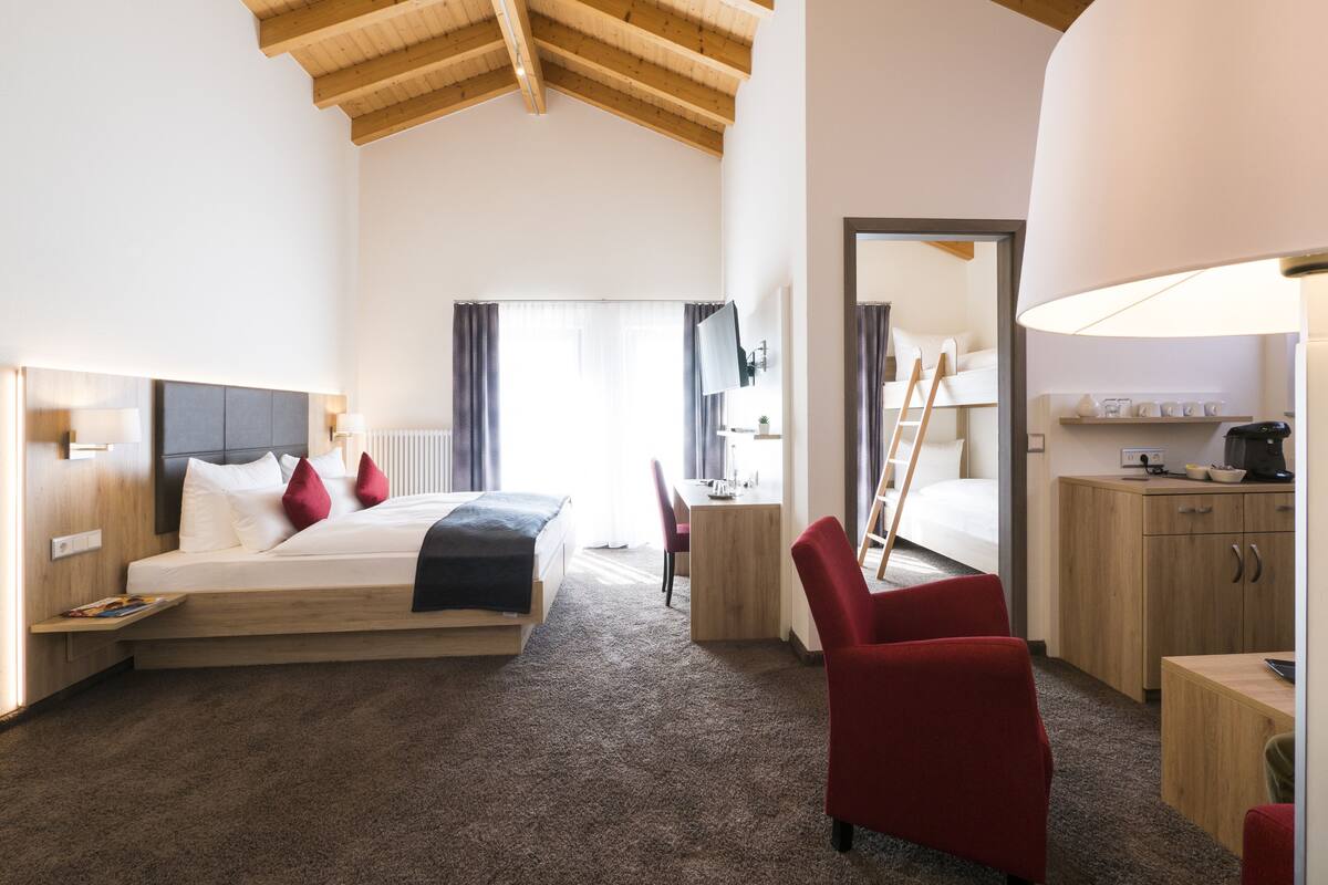 Une chambre d’hôtel comprenant un lit, un bureau, une chaise, une armoire et une lampe.