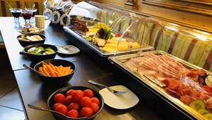 Un buffet proposant divers plats, notamment des concombres en tranches, des tomates cerises et du jambon.