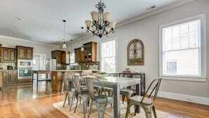 A spacious kitchen with wooden cabinets, a central island, and a chandelier.