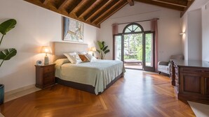 Une chambre à coucher avec un lit, des tables de chevet, une grande fenêtre et une vue sur l’extérieur.