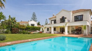 Une grande piscine, une pelouse verdoyante et une maison à deux étages dotée d’un balcon.