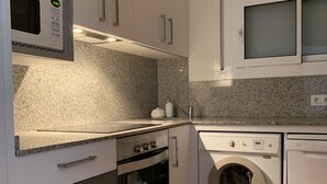 A compact kitchen with a microwave, oven, and washing machine. - Apartment in Torre Valentina, 2 min from the beach (Calonge)