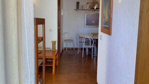 A hallway with a dining area, a wooden door, and a wall-mounted light fixture. - Apartment in Torre Valentina, 2 min from the beach (Calonge)