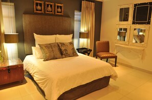A neatly arranged bedroom with a large bed, a chair, and a small table.