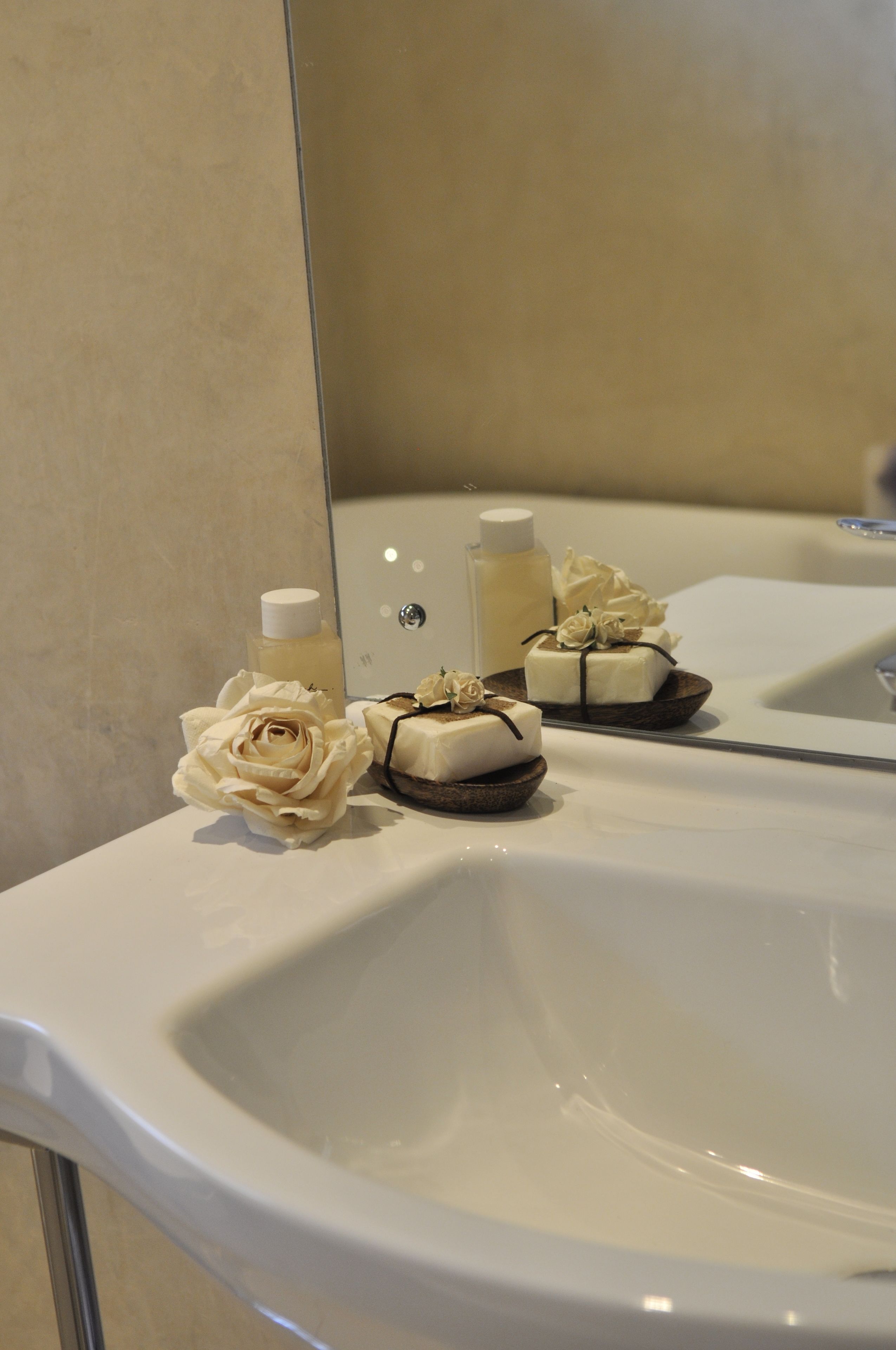 A bathroom sink with toiletries and a decorative rose.