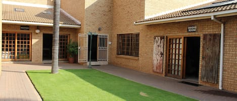 A courtyard with a reception area and a dining room, surrounded by brick buildings with a tiled roof.