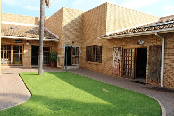 A courtyard with a reception area and a dining room, surrounded by brick buildings with a tiled roof.