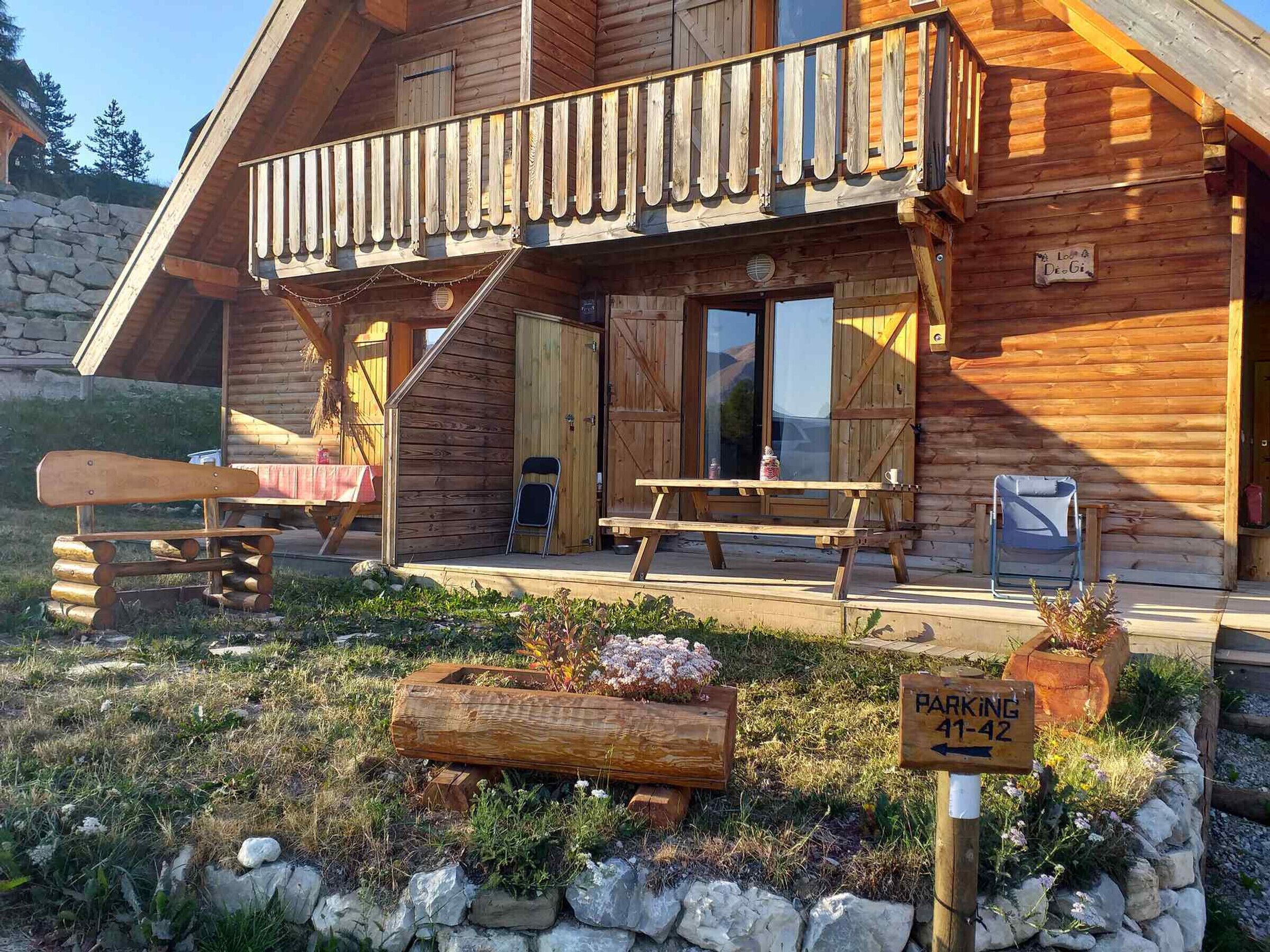 A wooden cabin with a balcony, a picnic table, and a sign indicating parking spots 41-42.