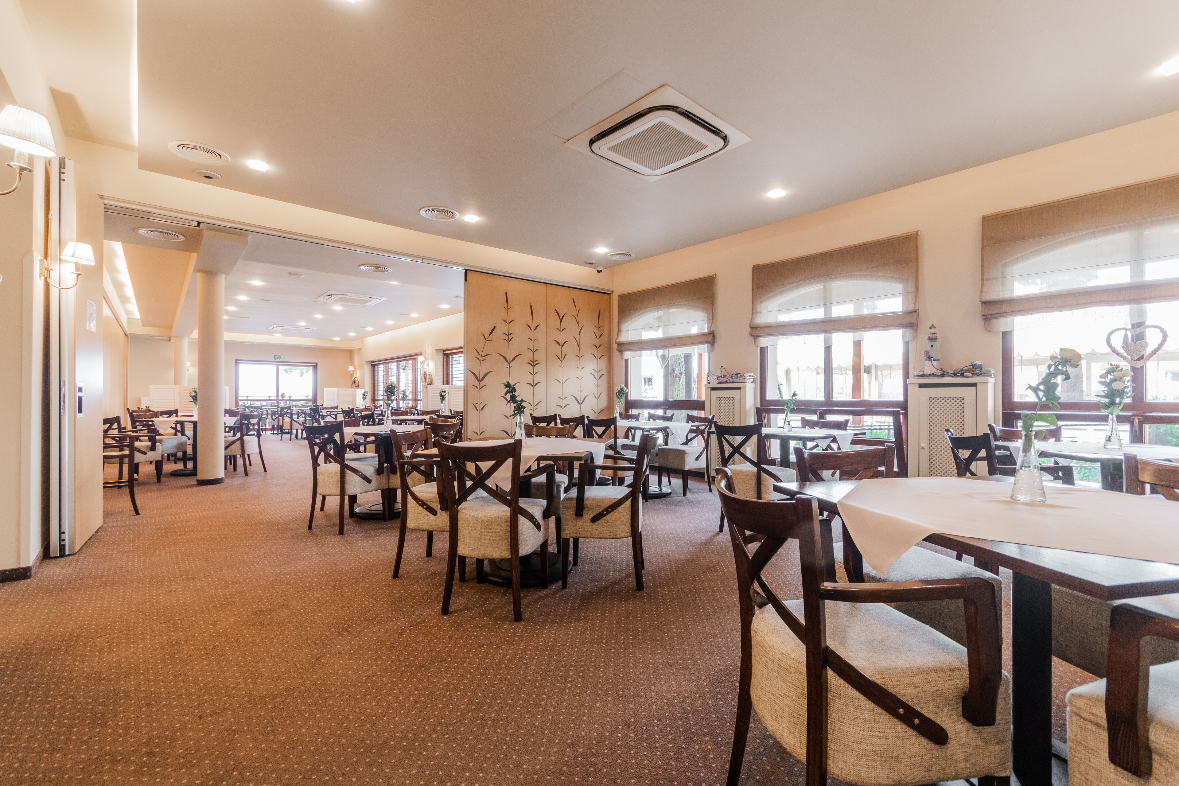 A spacious restaurant with multiple dining areas, large windows, and a variety of seating arrangements.