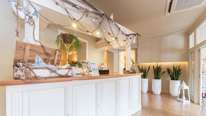 A reception area with a wooden counter, potted plants, and a decorative rope arch.