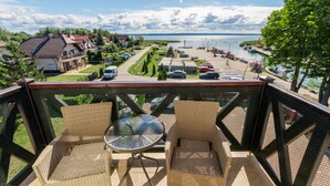 A balcony with wicker furniture overlooking a marina with boats and a residential area.