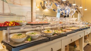 A buffet with various food items and a decorative sailboat mural on the wall.