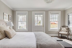 Cozy retreat with a large bed, chandelier, and comfortable chair.