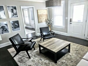 Relax in this stylish living room with a large coffee table, two comfortable armchairs, and a striking abstract art piece.