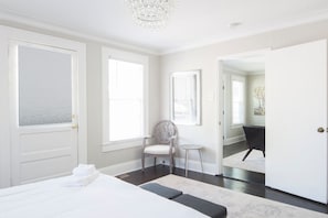 Une chambre d’hôtel avec un lit, une chaise, une petite table et une porte donnant sur une autre pièce.