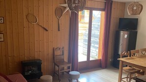 Un intérieur en bois comprenant un canapé, une table à manger avec des chaises, un petit tabouret, un banc et un téléviseur.