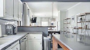 Una cocina moderna con armarios blancos, encimera de mármol y una isla central.