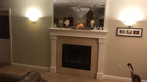 A living room with a fireplace, a sofa, and wall sconces.