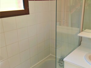A bathroom with white tiles, a glass shower enclosure, and a white sink. - Charming Chalet in Les Flocons du Soleil - 3 Rooms, 7 Guests, Pool & Sauna Access (La Joue du Loup)