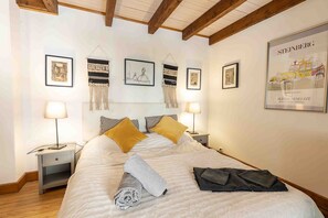 Ein Hotelzimmer mit einem Bett, zwei Nachttischen, einem Kopfteil und gerahmten Kunstwerken an den Wänden.