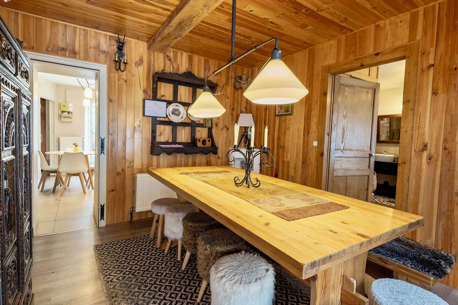 Un interior rústico de madera con una mesa isla central, iluminación colgante y una zona de estar acogedora.