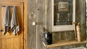 A wooden wall with a framed picture of Peter Klasen, a black lantern, and a copper gas cylinder on a shelf. - Large charming refuge at the water's edge in Gérardmer. Spa / sauna / Wifi (Gérardmer)