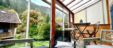 Una habitación con un ventanal amplio, una mesa, sillas y una cama.