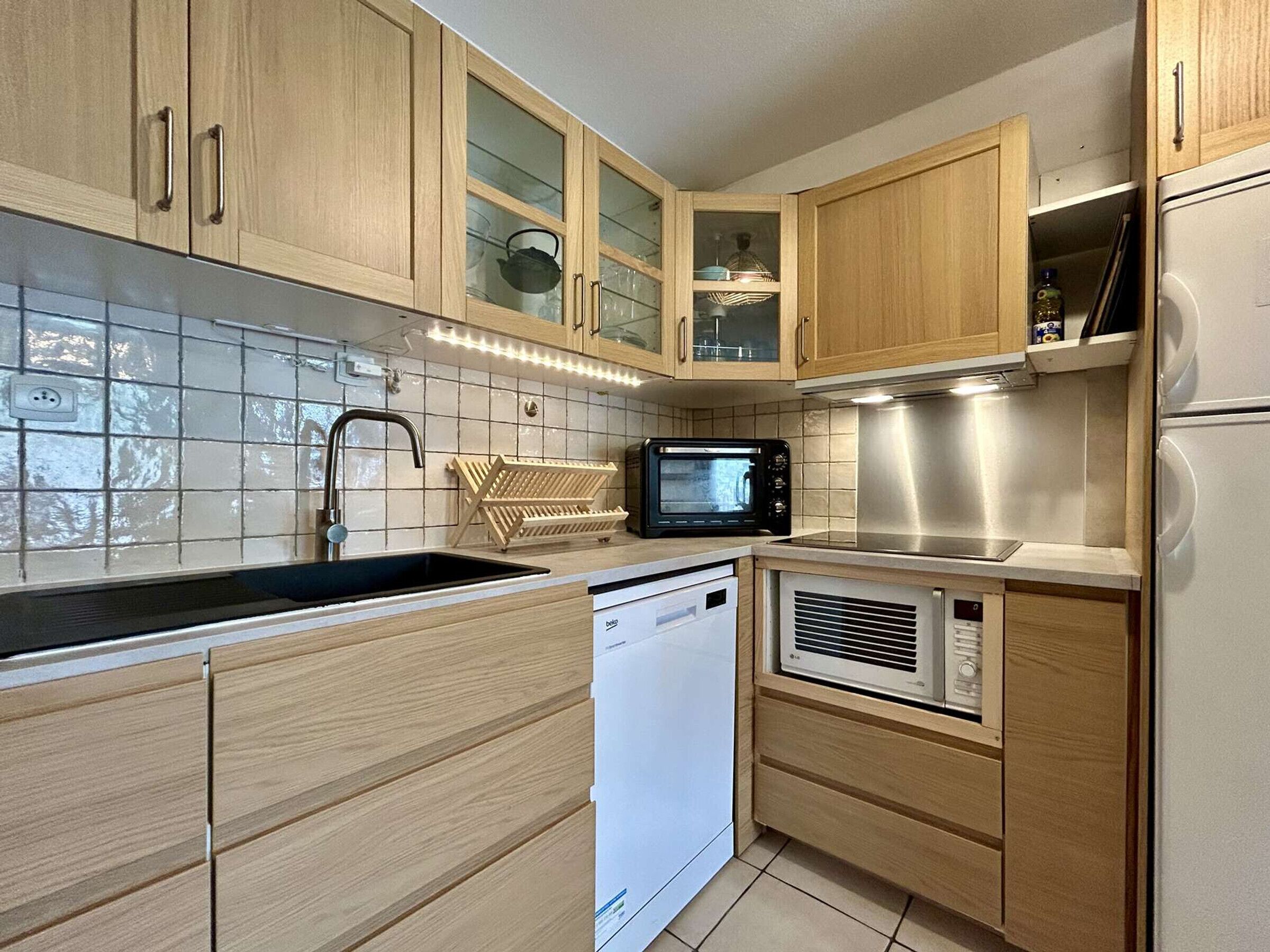 A kitchen with wooden cabinets, a microwave, a dishwasher, and a stainless steel range hood.