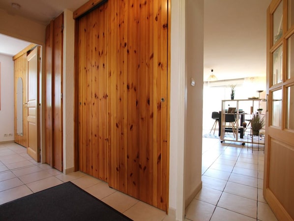 A hallway with wooden doors and a tiled floor.