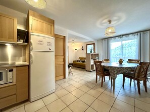 A kitchen with a refrigerator, wooden cabinets, and a dining area with a table and chairs.