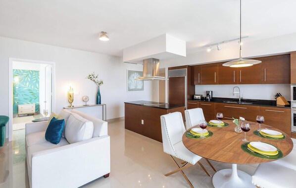 Una cocina moderna con armarios de madera, una isla central y un comedor con una mesa redonda dispuesta para seis personas.