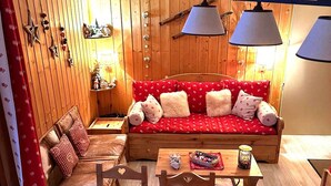 Une pièce chaleureuse avec un canapé en bois, une petite table sur laquelle se trouve un panier, et une chaise.