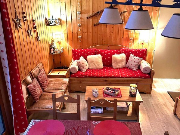 A cozy room with a wooden sofa, a small table with a basket, and a chair.