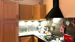 Une cuisine dotée de meubles en bois, d’une hotte noire, d’un évier et de divers appareils de cuisine.