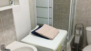 Een kleine badkamer met een wastafel, wasmachine en toilet.