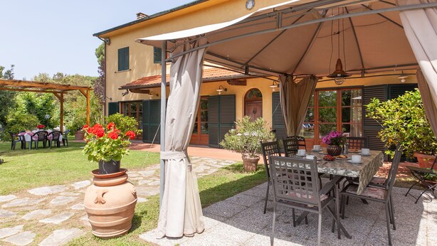 An outdoor patio area with a table and chairs, surrounded by potted plants and a pergola. - Apartment "Piccolo paradiso" (Crespina, Pisa)
