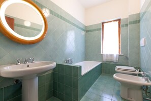 Tina con regadera, bidet, toallas, papel de baño 