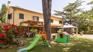 A house with a patio, a play area with a slide, and a small green playhouse. - Apartment "Piccolo paradiso" (Crespina, Pisa)