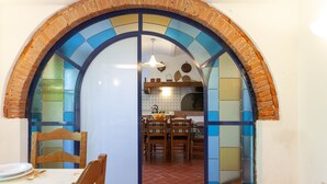 A dining area with a brick archway leading to a kitchen. - Apartment "Piccolo paradiso" (Crespina, Pisa)
