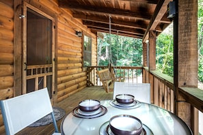 A wooden cabin with a porch, a table with chairs, and a hanging chair. - Mosey Bear, Hot Tub, WIFI, $560 FREE tickets each paid day!!! (Sevierville)