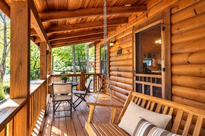 A wooden cabin with a porch, a dining table, chairs, and a swing. - Mosey Bear, Hot Tub, WIFI, $560 FREE tickets each paid day!!! (Sevierville)