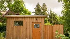 Eine Holzhütte mit Tür, Fenstern und einer kleinen Veranda.